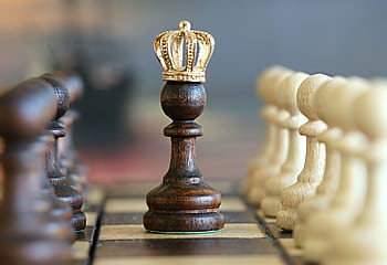A brown pawn with a crown stands prominently on a chessboard, symbolizing strategic play. HD wallpaper