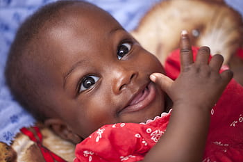 Close-up portrait of a happy baby smiling in a bright red outfit, showcasing joy and innocence. HD wallpaper
