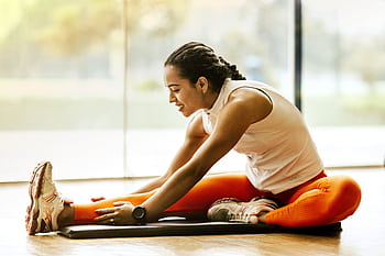 A woman enjoying a yoga stretch indoors, promoting a healthy lifestyle. HD wallpaper