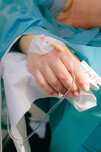 Close-up of a patient's hand receiving intravenous therapy in a hospital setting. HD phone wallpaper