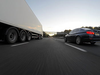 Cars and a truck speed along a highway under the clear sky, showcasing transportation dynamics. HD wallpaper