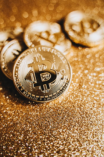 Close-up of Bitcoin coins on a glittering gold background representing cryptocurrency and finance. HD phone wallpaper