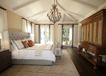 Stylish bedroom interior featuring a rustic chandelier, cozy bedding, and elegant wooden furniture. HD wallpaper
