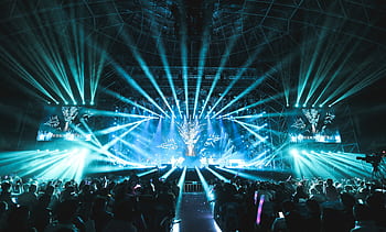 Lively concert scene featuring dazzling stage lights and a large, enthusiastic crowd enjoying the event. HD wallpaper