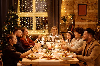 Family celebrating Christmas with dinner and sparklers, creating joyful holiday atmosphere indoors. HD wallpaper