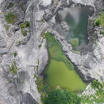 Aerial graph showcasing eroded rocky terrain with distinct green bodies of water, offering a unique geological perspective. HD phone wallpaper