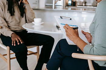Two professionals engaged in a consultation, one taking notes on a clipboard. HD wallpaper