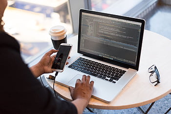 Developer working remotely, coding on a laptop with in hand, showcasing modern work culture. HD wallpaper