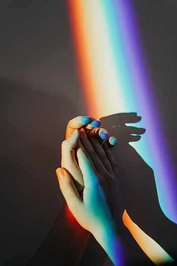 Artistic representation of unity with hands holding under colorful rainbow light reflection. HD phone wallpaper