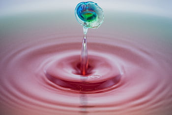 Colorful water droplet captured mid-splash creating intricate ripples. HD wallpaper