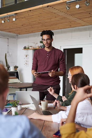 Young professionals engaged in a brainstorming session in a modern office setting. HD phone wallpaper
