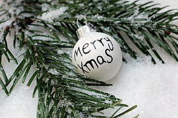 Close-up of a frosted pine branch and Merry Xmas ornament in the snow. HD wallpaper