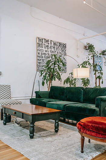 Inviting living room featuring a green velvet sofa, lush indoor plants, and a modern aesthetic. HD phone wallpaper