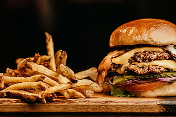 Mouthwatering cheeseburger and crispy fries on a wooden board, perfectly capturing fast food appeal. HD wallpaper