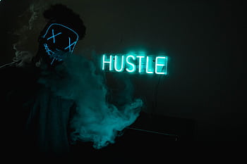 A neon green 'HUSTLE' sign illuminates a mysterious masked figure with smoke. HD wallpaper