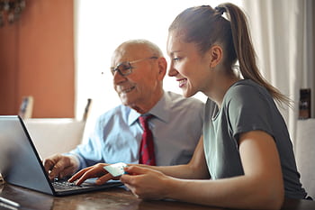 A senior adult and young woman happily shopping online with a laptop at home. HD wallpaper
