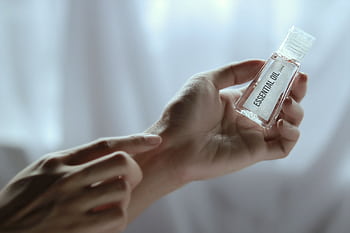 Close-up of a hand holding an essential oil bottle, ideal for wellness and skincare concepts. HD wallpaper