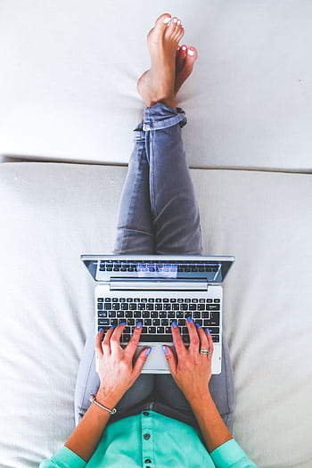Overhead view of a person working on a laptop while relaxing at home, embodying modern remote work lifestyle. HD phone wallpaper