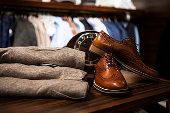 Stylish leather shoes displayed with gray clothing in a chic boutique setting. HD wallpaper