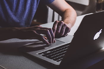 Close-up of hands typing on a laptop in a dark office setting. Perfect for business and technology themes. HD wallpaper