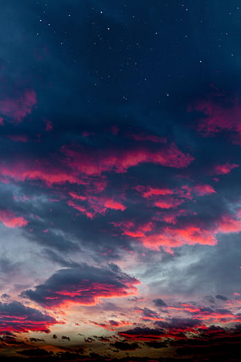 A breathtaking view of a dramatic sky with vibrant clouds and visible stars at night. HD phone wallpaper