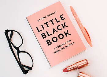 Pink flat lay featuring a book, glasses, pen, and lipstick over a white background. HD wallpaper
