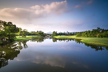 Peaceful golf course landscape with a reflective lake and serene surroundings. HD wallpaper