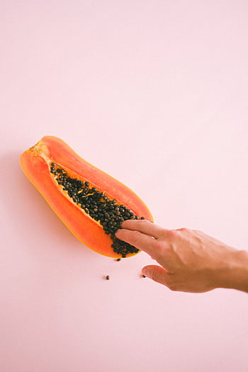 Aesthetic composition of a papaya and hand on soft pink backdrop, offering a sensual visual experience. HD phone wallpaper