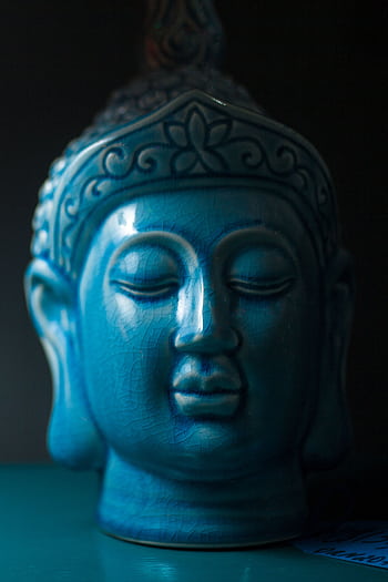 Close-up view of a blue ceramic Buddha head sculpture symbolizing peace and spirituality. HD phone wallpaper