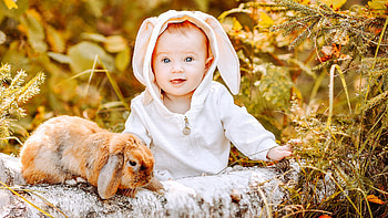 Cute Child Baby With Bunny Dress Is Sitting Near Rabbit In Plants Background Cute HD wallpaper