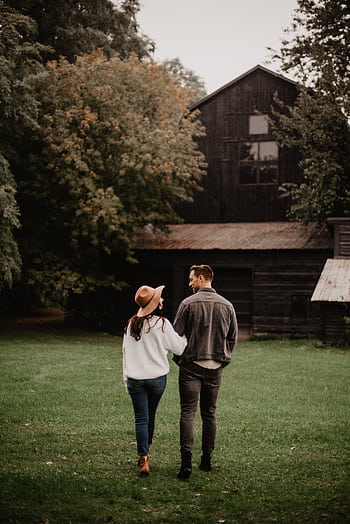 A couple walks through a grassy area towards a rustic barn, capturing a romantic autumn ambiance. HD phone wallpaper