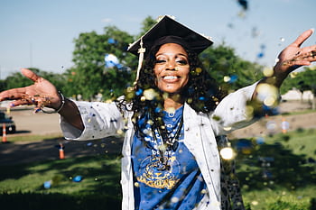 African American woman celebrating graduation with confetti outdoors, filled with happiness and success. HD wallpaper