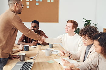 A diverse team in a modern office working together on a project, showcasing teamwork and collaboration. HD wallpaper