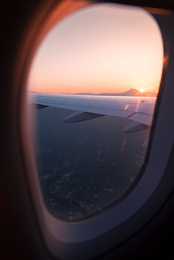 Airplane wing view through window during sunset, capturing a serene sky and landscape below. HD phone wallpaper
