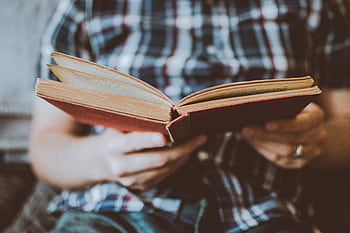 Close-up of hands holding and reading an antique book indoors, symbolizing knowledge and learning. HD wallpaper