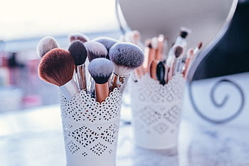 A collection of makeup brushes in decorative holders, ideal for beauty and fashion themes. HD wallpaper