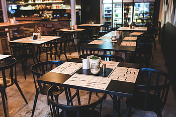 Warm and inviting café with tables, chairs, and a cozy ambiance. HD wallpaper