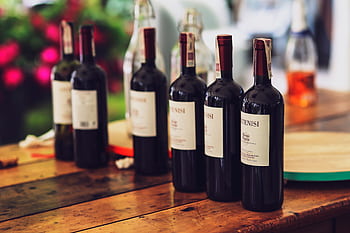 Cozy dinner setup featuring multiple wine bottles on a wooden table, ideal for special occasions. HD wallpaper
