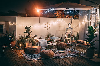 Inviting outdoor patio setup at night featuring cozy seating, string lights, and decor for perfect relaxation. HD wallpaper