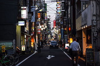 Street scene with city lights and signs in Japan at dusk, capturing urban life and transportation. HD wallpaper