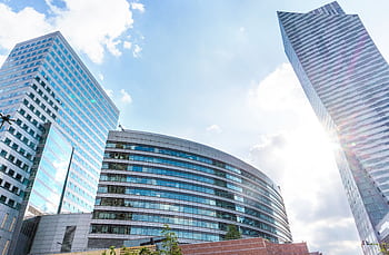 Urban cityscape with modern skyscrapers reflecting sunlight against a blue sky. HD wallpaper