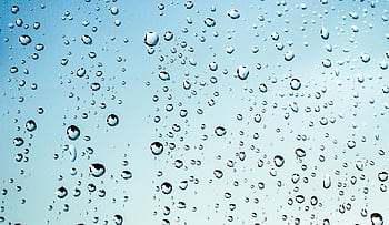 Close-up view of water droplets on glass against a blue sky background. HD wallpaper