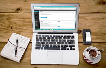 A cozy home office scene with a laptop, notebook, smart, and coffee, perfect for productivity. HD wallpaper