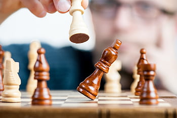 Close-up of a chess game with a focused player, emphasizing strategy and competition. HD wallpaper