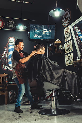 A barber skillfully cutting a man's hair in a trendy, well-decorated barbershop. HD phone wallpaper