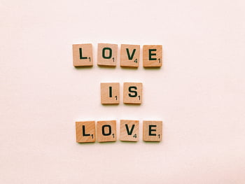 Wooden letter tiles forming 'Love is Love', symbolizing inclusion and pride. HD wallpaper