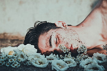A contemplative of a man lying among white flowers, conveying introspection. HD wallpaper