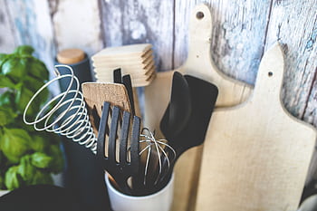 Collection of kitchen utensils including spatula, whisk, and chopping boards against a rustic background. HD wallpaper