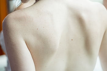A detailed close-up of a woman's back, highlighting skin texture and subtle freckles. HD wallpaper