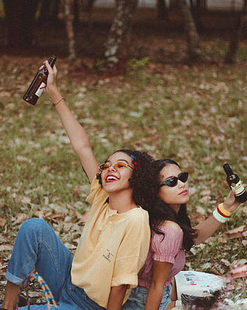 Two women enjoying a fun picnic in the park, raising drinks and celebrating friendship. HD phone wallpaper